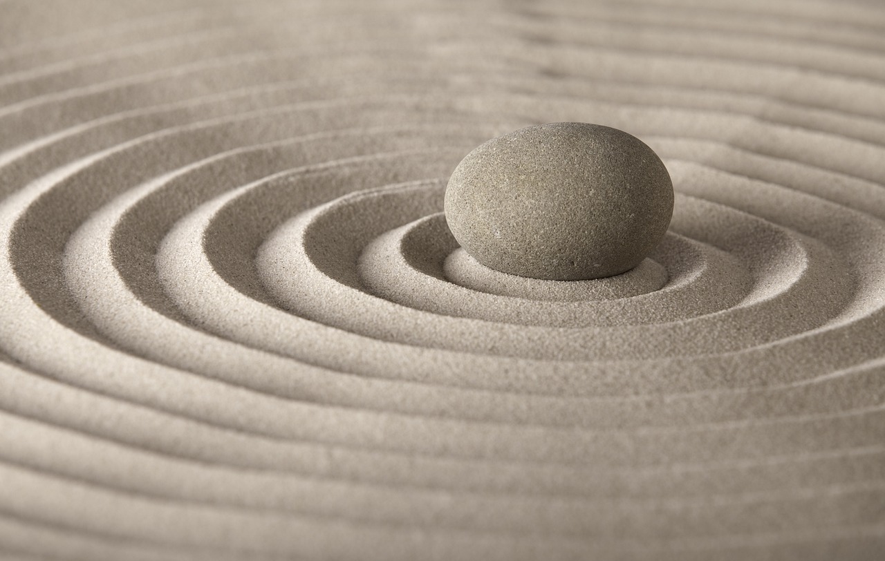 Un galet posé dans un cercle de sable représentant le bien-être